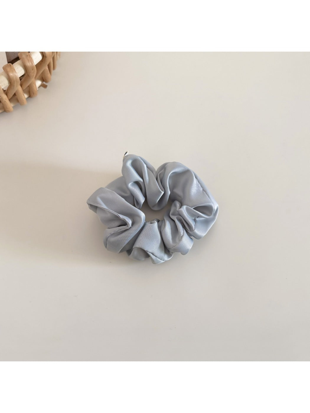 Satin bow scrunchie on a wooden surface with soft natural lighting