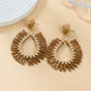 Detailed shot of raffia weave pattern on oval drop earring with gold-tone hardware