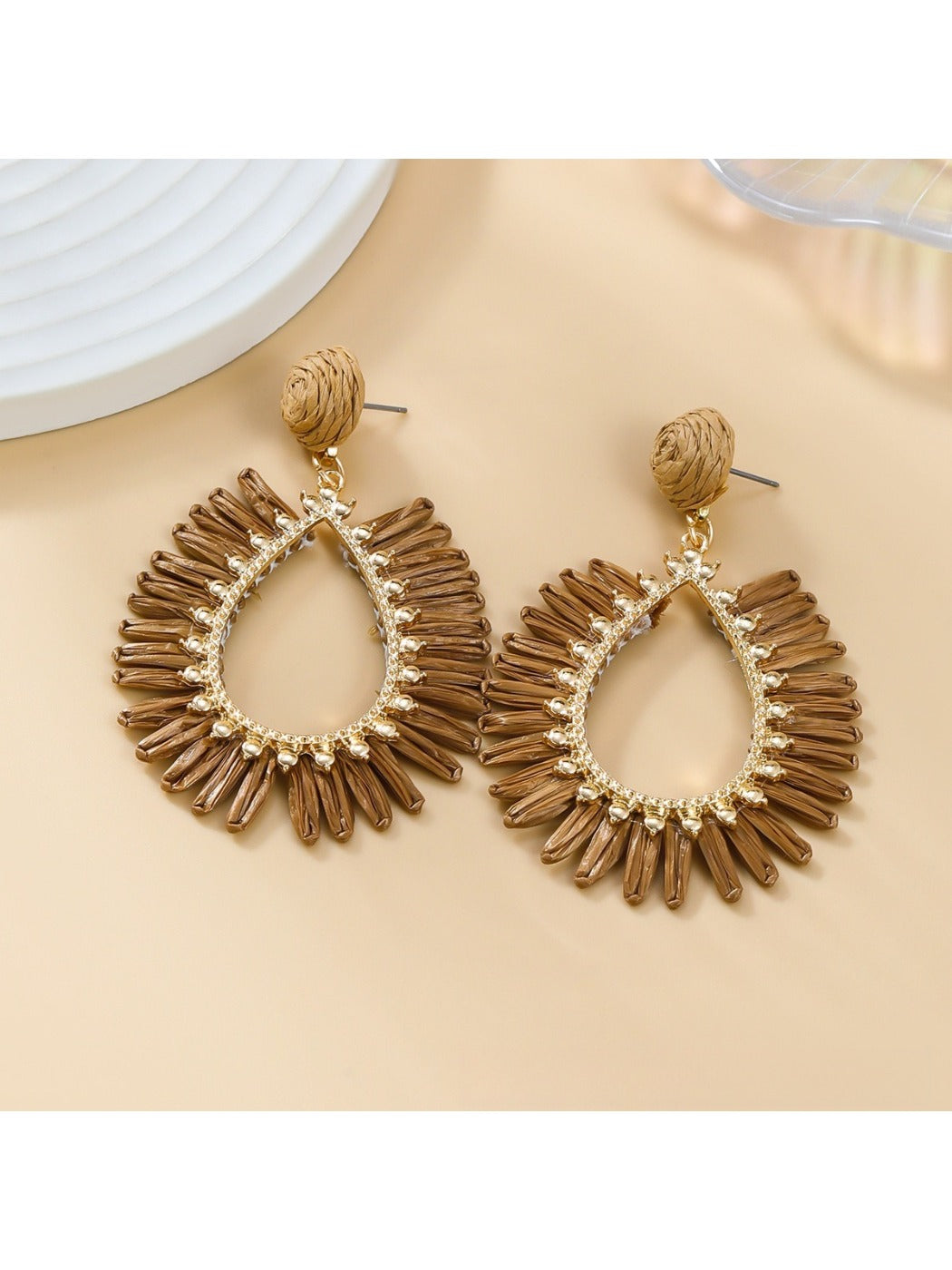 Detailed shot of raffia weave pattern on oval drop earring with gold-tone hardware