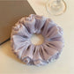 Close-up of a chic purple reflective tulle scrunchie with gathered fabric texture