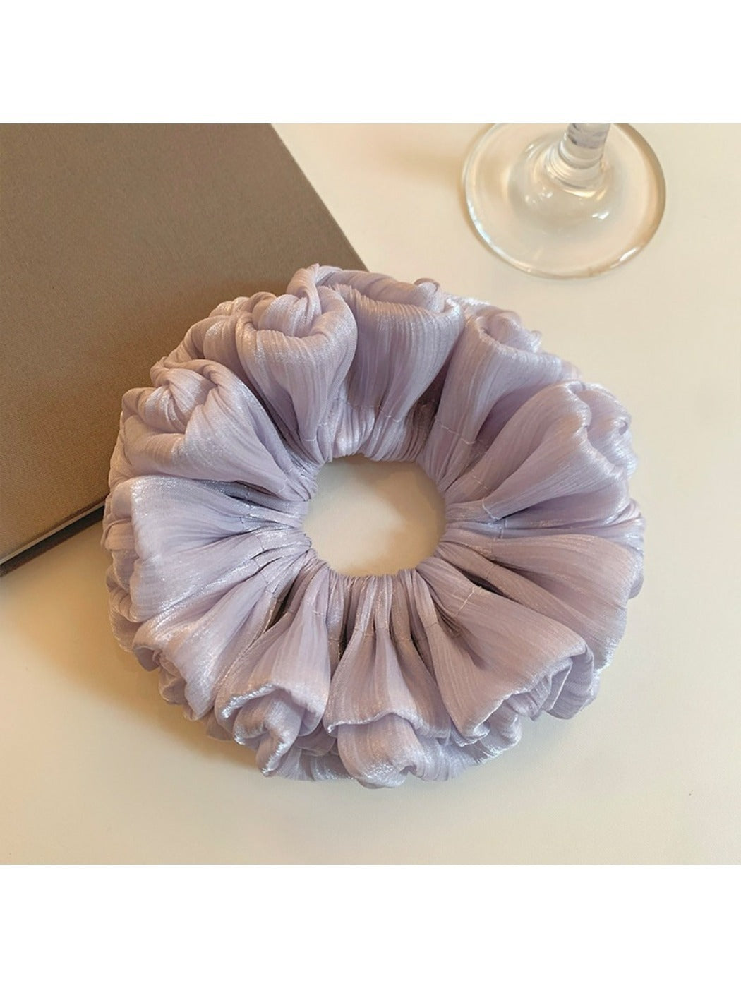 Close-up of a chic purple reflective tulle scrunchie with gathered fabric texture