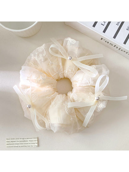 Gifty scrunchie worn on a wrist, showcasing its size and bow decoration