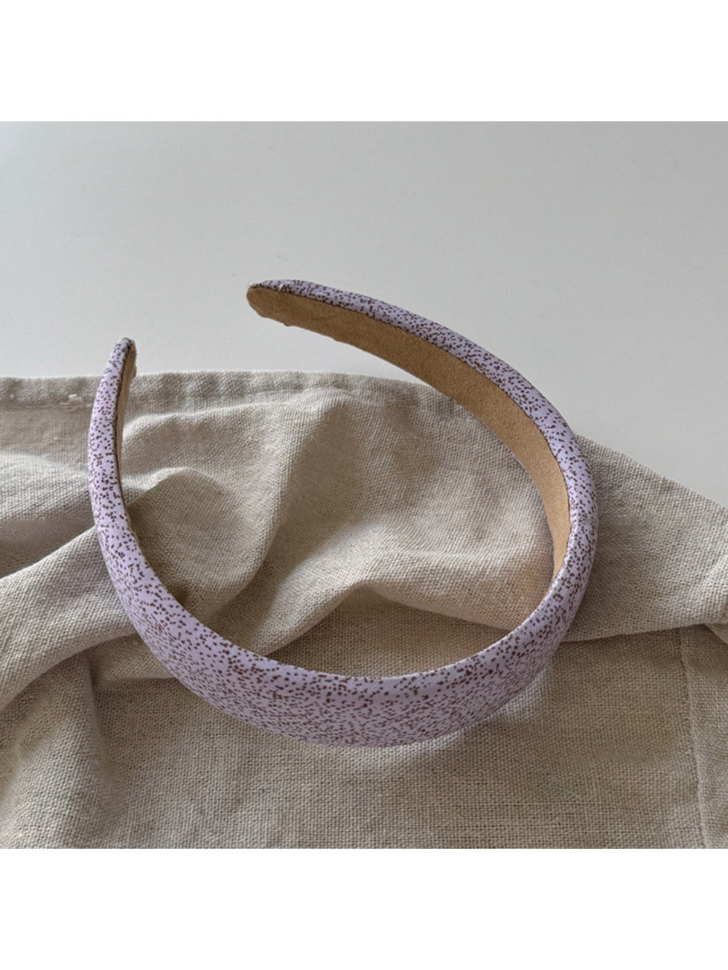 Purple wide edge headband folded to show flexibility and material