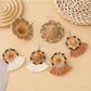 Pair of straw hat shaped earrings displayed on a jewelry stand