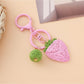Strawberry charm keychain placed on a pastel pink background for a cute aesthetic