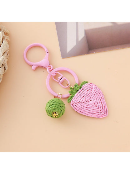 Strawberry charm keychain placed on a pastel pink background for a cute aesthetic
