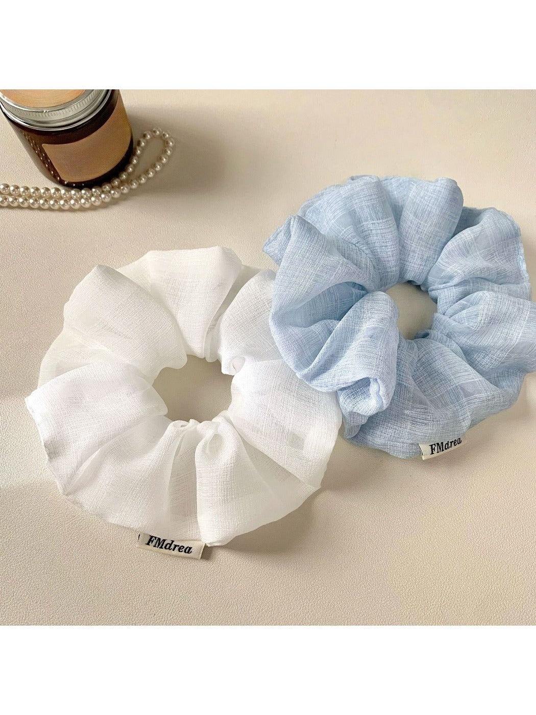 Side view of a modern ruched scrunchie in a solid color on a flat surface