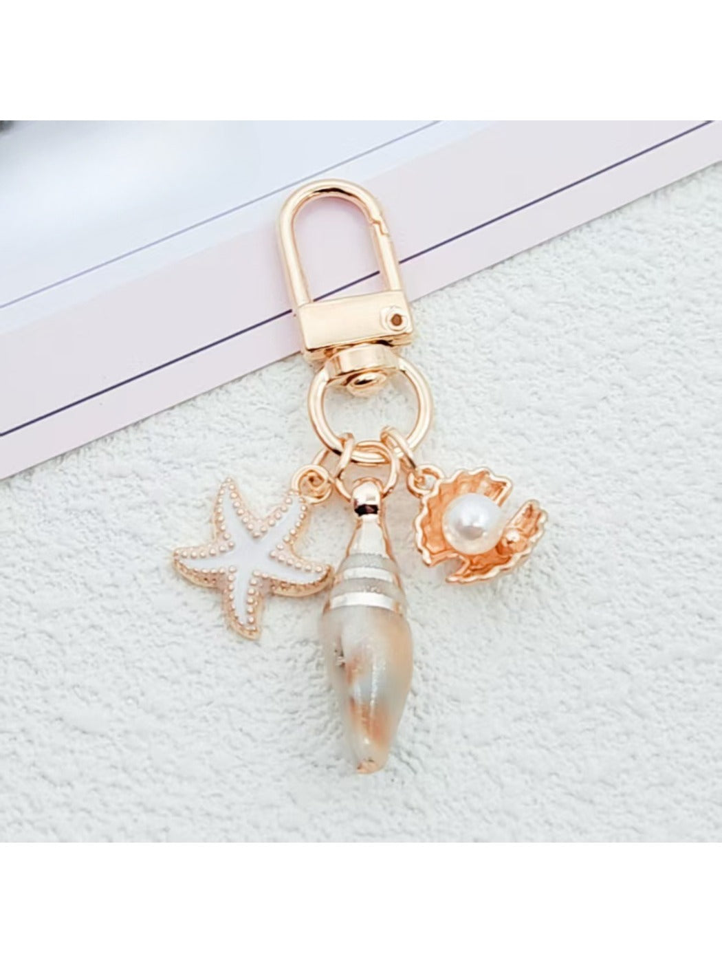Side view of gold conch keychain highlighting its curved shell design