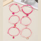 Lovra pink pendant layered bracelet with delicate chains and small charms on a white background