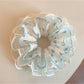Close-up of Gifty sweet floral ruffled scrunchie with pink and white flowers on fabric