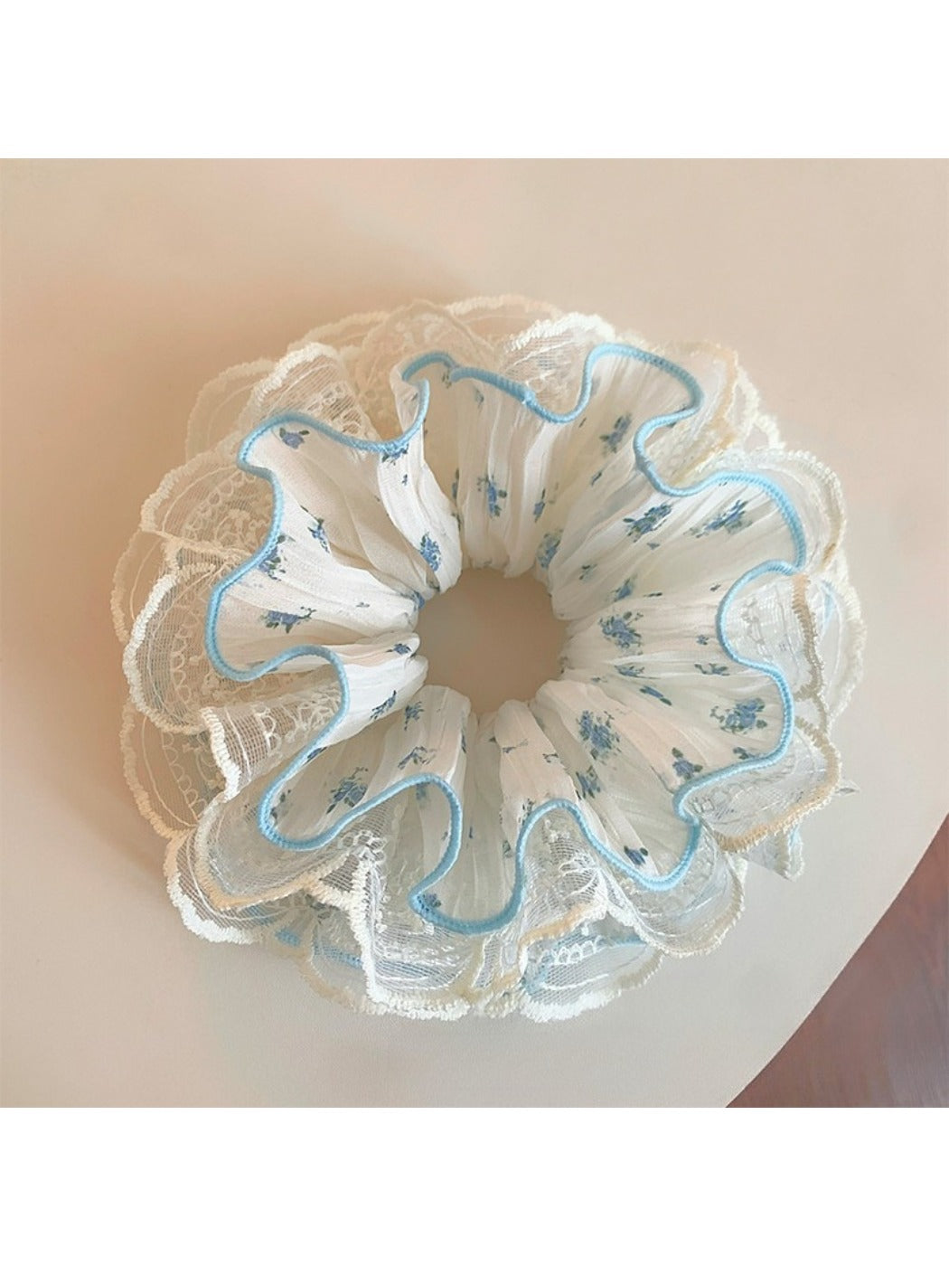 Close-up of Gifty sweet floral ruffled scrunchie with pink and white flowers on fabric