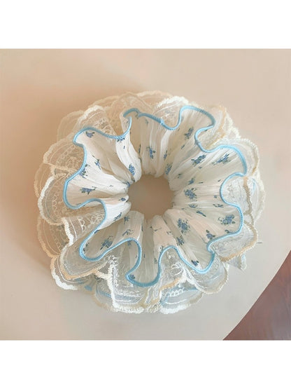 Close-up of Gifty sweet floral ruffled scrunchie with pink and white flowers on fabric