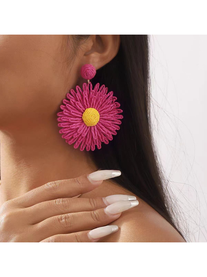 Colorful floral raffia earrings hanging on a decorative stand