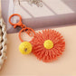 Sunflower keychain with metal ring and natural raffia petals in bright lighting