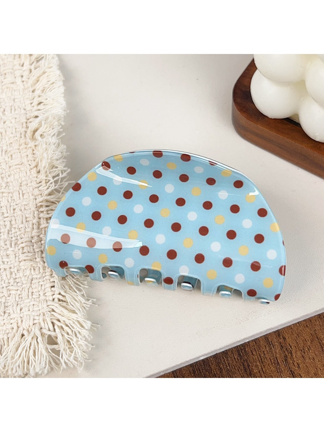 Blue polka dot hair claw clip displayed on a fabric background
