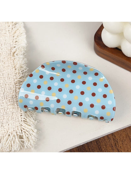 Blue polka dot hair claw clip displayed on a fabric background