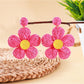 Top view of earedge pastel colored knitted flower earrings on a wooden surface