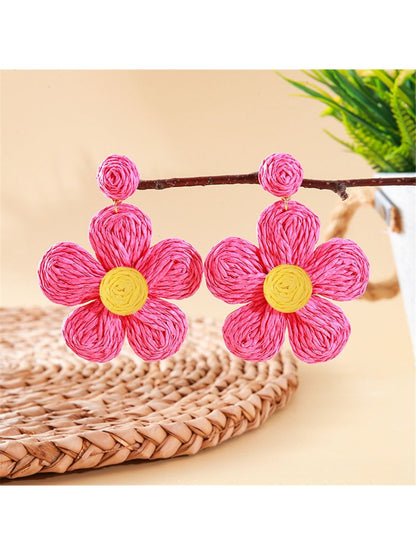 Top view of earedge pastel colored knitted flower earrings on a wooden surface