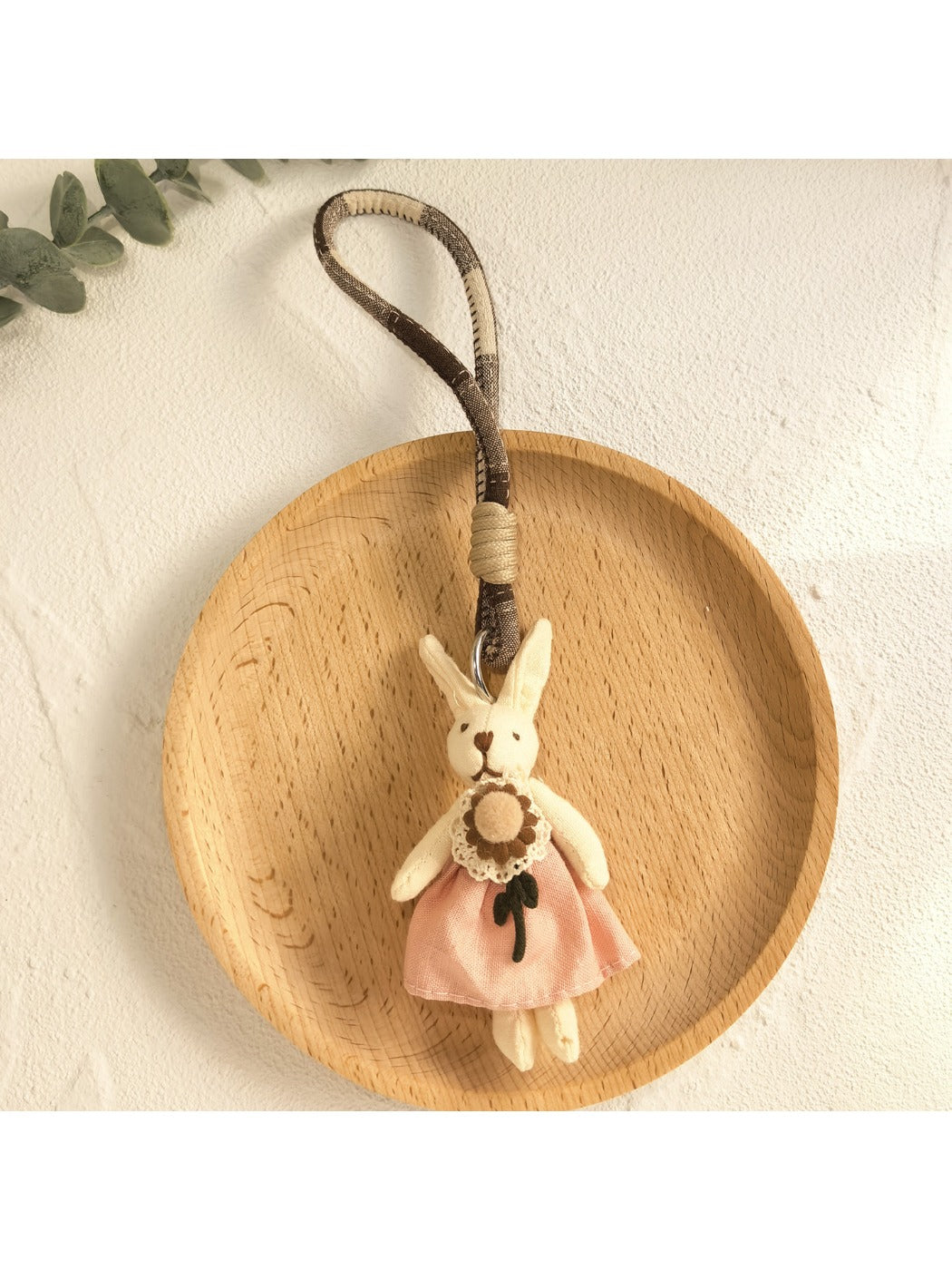 Hand holding the minimalist bunny pendant keychain with natural lighting