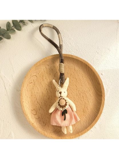 Hand holding the minimalist bunny pendant keychain with natural lighting