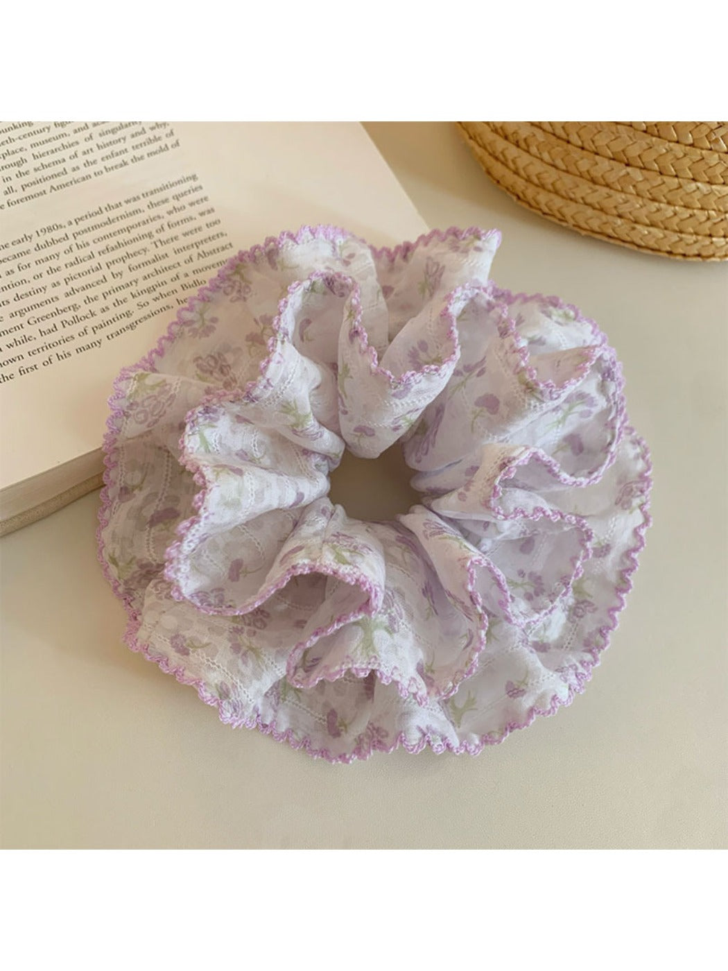 Purple floral print scrunchie displayed on a flat surface with soft lighting