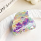 Claw clip placed on a white surface showing its colorful crescent design
