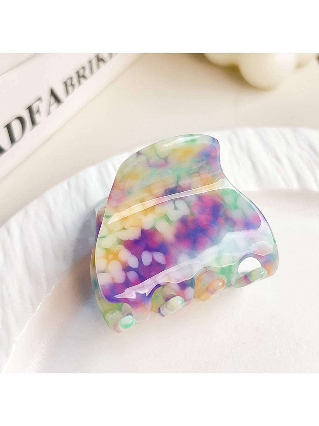 Claw clip placed on a white surface showing its colorful crescent design