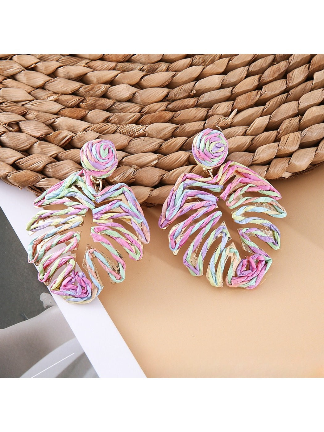 Earedge raffia woven hollow leaf shaped earrings hanging on a jewelry stand