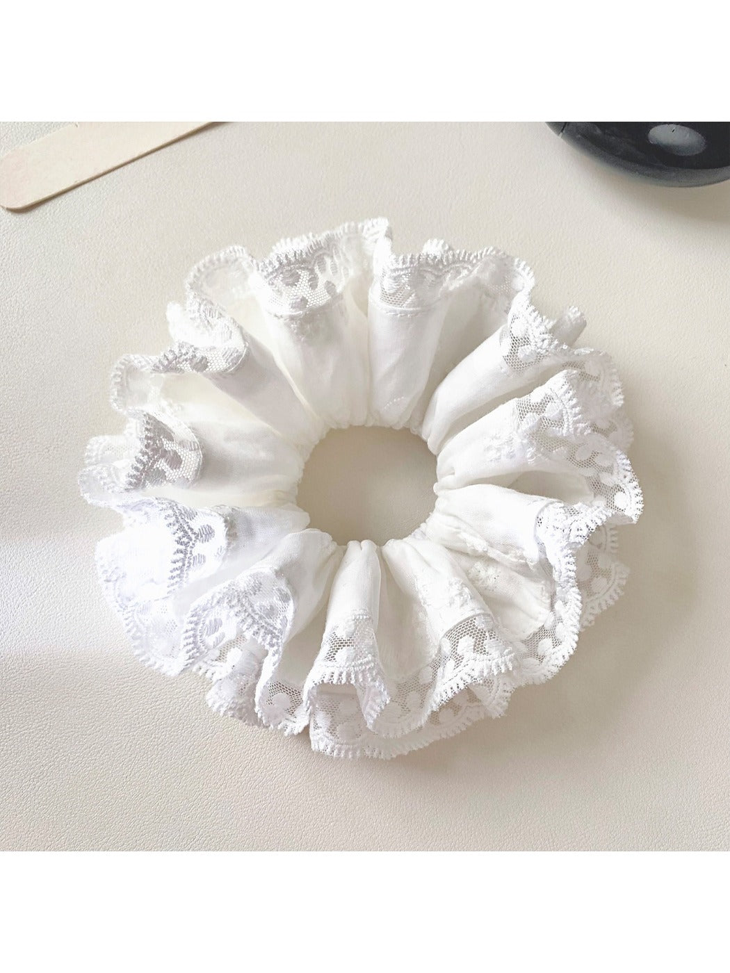 White scrunchie with lace trim wrapped around a ponytail