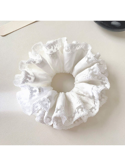 White scrunchie with lace trim wrapped around a ponytail
