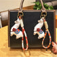 Alpaca charm keychain attached to a set of keys on a wooden surface