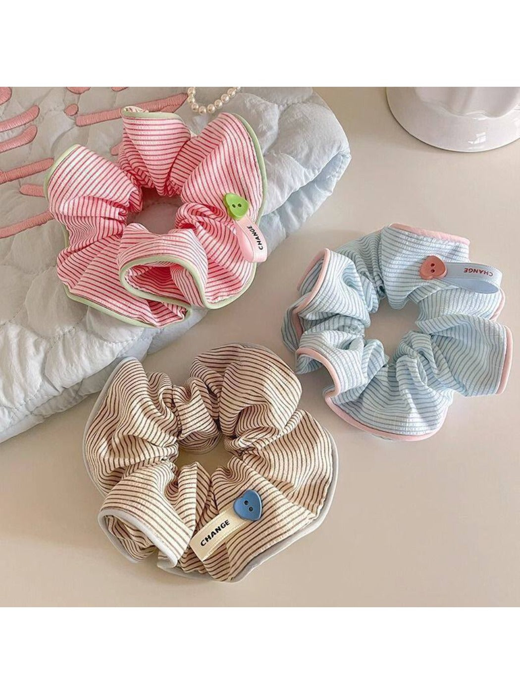 Gifty minimalist scrunchie with white and beige stripes on a white background