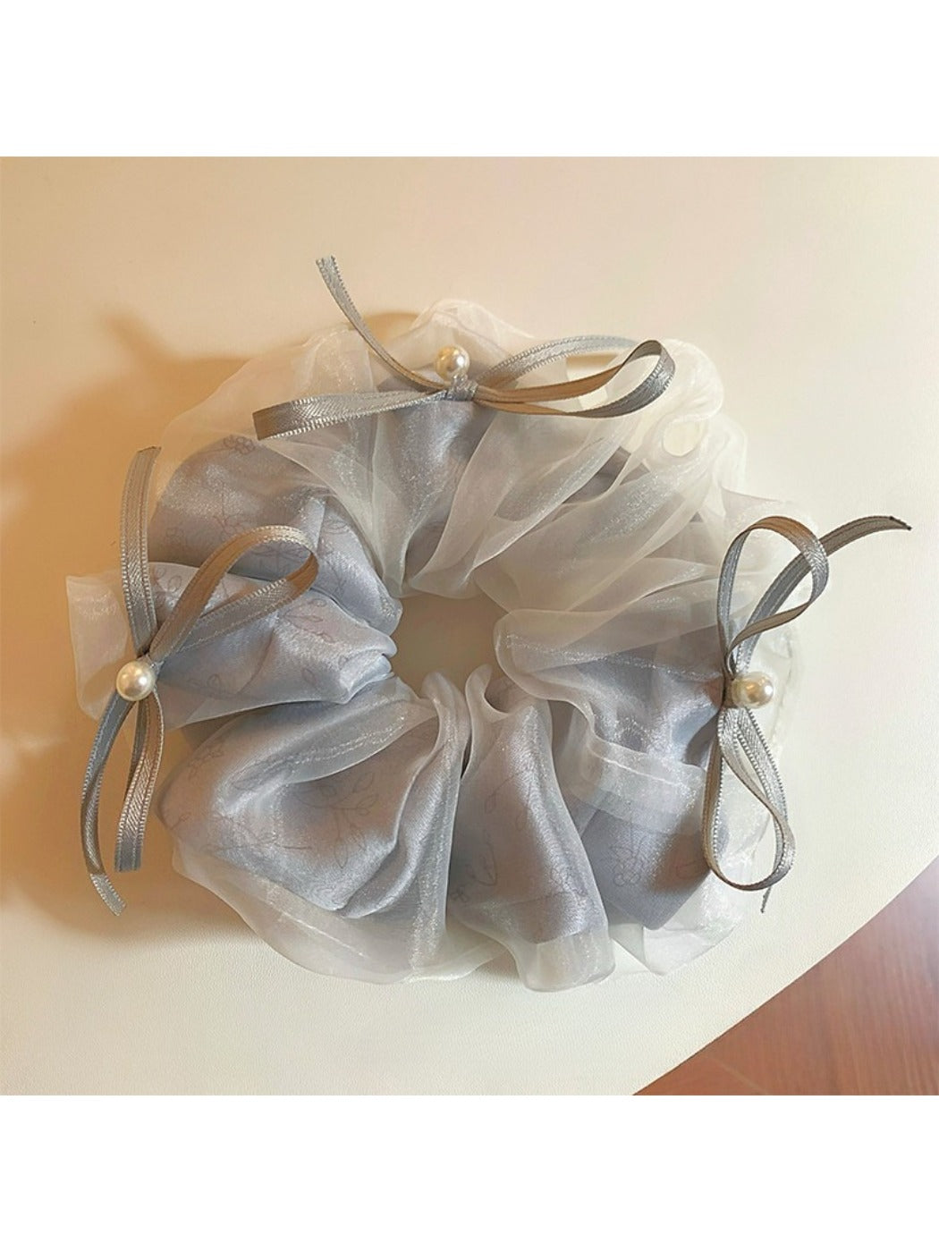 Gifty tulle ribbon bow scrunchie worn on a wrist as a fashion accessory