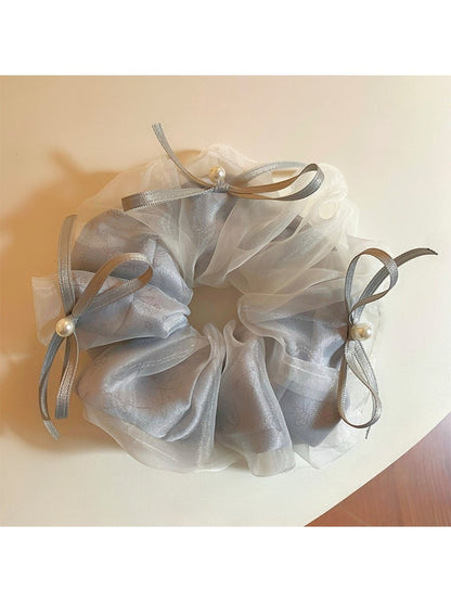 Gifty tulle ribbon bow scrunchie worn on a wrist as a fashion accessory