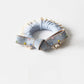 Bow hair ties in various colors stacked neatly on a white ceramic dish