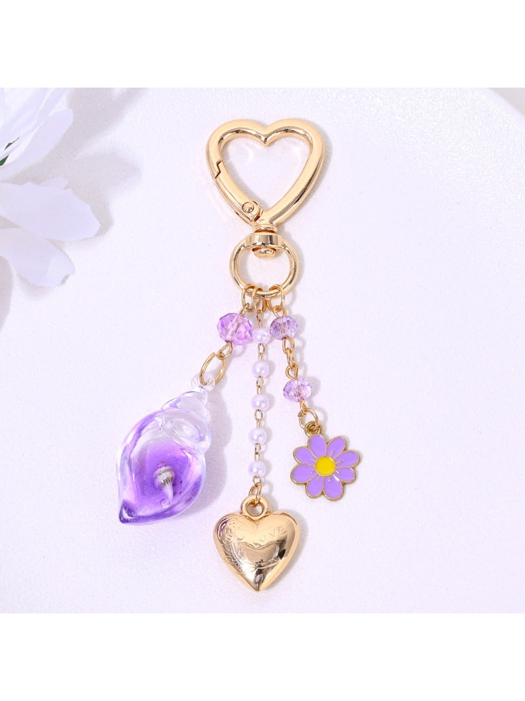 Flower shaped charm attached to gold keyring with heart charm