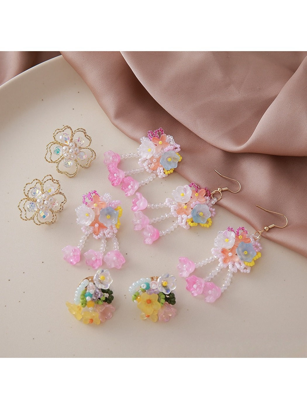 Close-up of small beaded flower-shaped earrings with white and gold beads