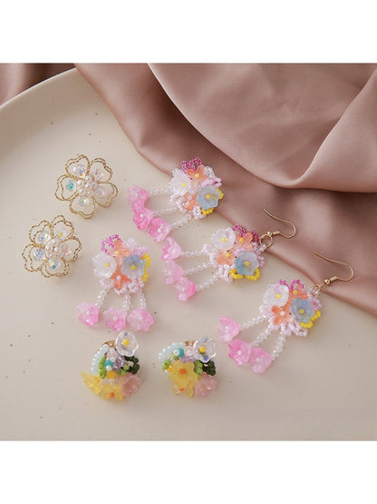 Close-up of small beaded flower-shaped earrings with white and gold beads