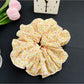 Black fabric scrunchie with white polka dots next to a small gift box