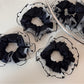 Close-up of black fabric scrunchie featuring white polka dot edging