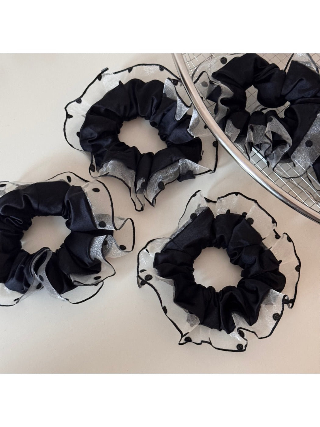 Close-up of black fabric scrunchie featuring white polka dot edging