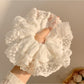 White ruffled scrunchie styled on a model's wrist with casual outfit