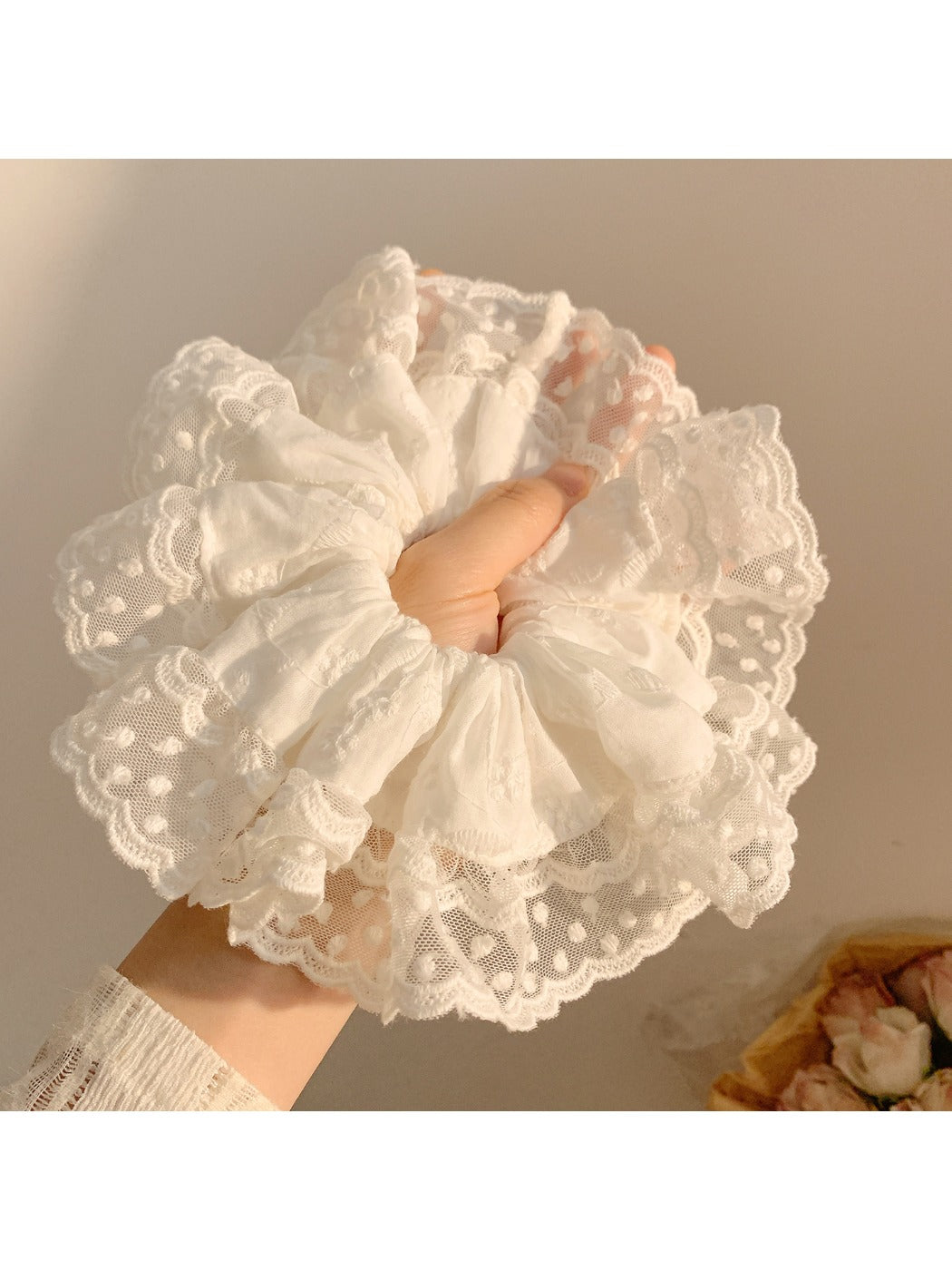 White ruffled scrunchie styled on a model's wrist with casual outfit