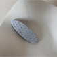 Beau pink hair clip with white polka dots held in hand for size reference