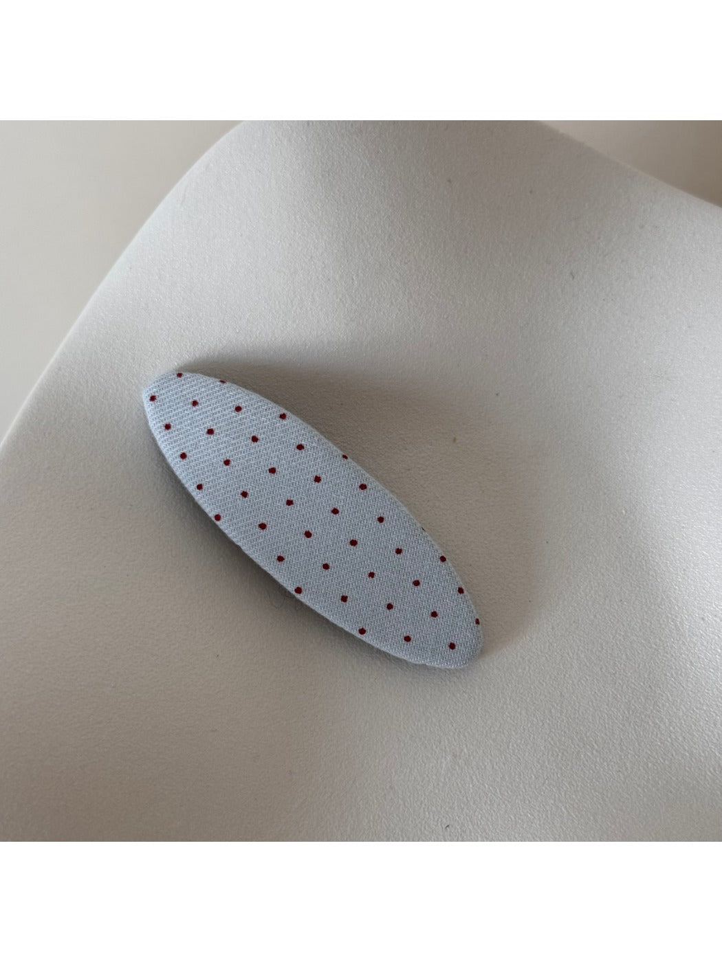 Beau pink hair clip with white polka dots held in hand for size reference