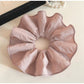 Soft pink fabric scrunchie stretched slightly to show elasticity