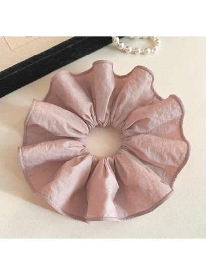 Soft pink fabric scrunchie stretched slightly to show elasticity