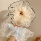 Close-up of elegant beige tulle scrunchie with delicate texture on white background