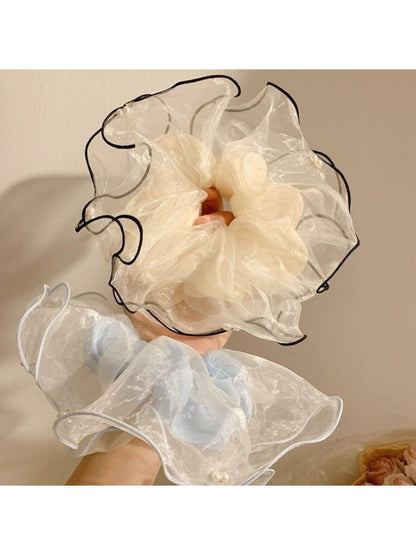 Close-up of elegant beige tulle scrunchie with delicate texture on white background