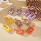 Close-up of Earedge raffia wrapped square earrings on white background